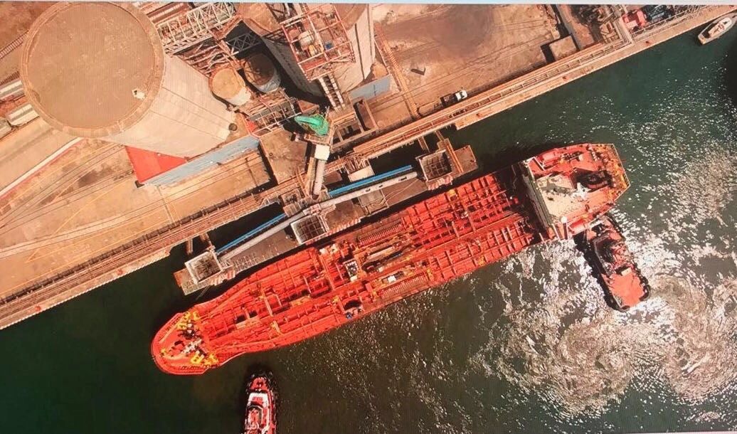 Aerial view of a red bulk liquid tanker docked at an industrial marine terminal